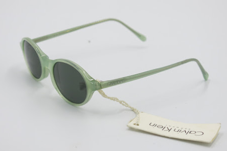 Green sunglasses with a visible brand tag on a light gray background