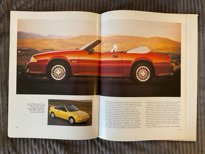 Open book showing a red convertible car on a mountainous landscape