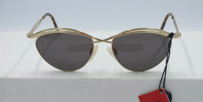 A pair of gold-framed sunglasses with lenses visible, displayed on a flat surface, accompanied by a red tag.