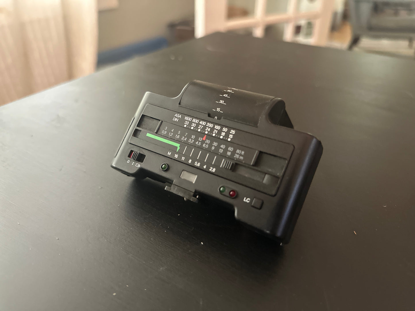 A vintage black radio transmitter or receiver with dials and switches, resting on a dark wooden table in an indoor setting.