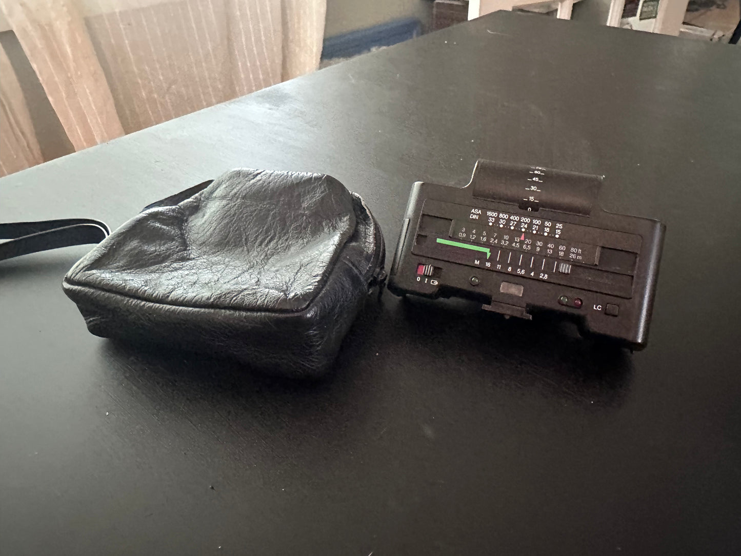 A vintage black plastic cassette tape reader next to its matching black protective case, resting on a dark tabletop.