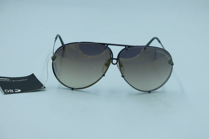 A pair of vintage Porsche sunglasses with a metallic frame and dark lenses, displayed on a flat surface with a tag attached.