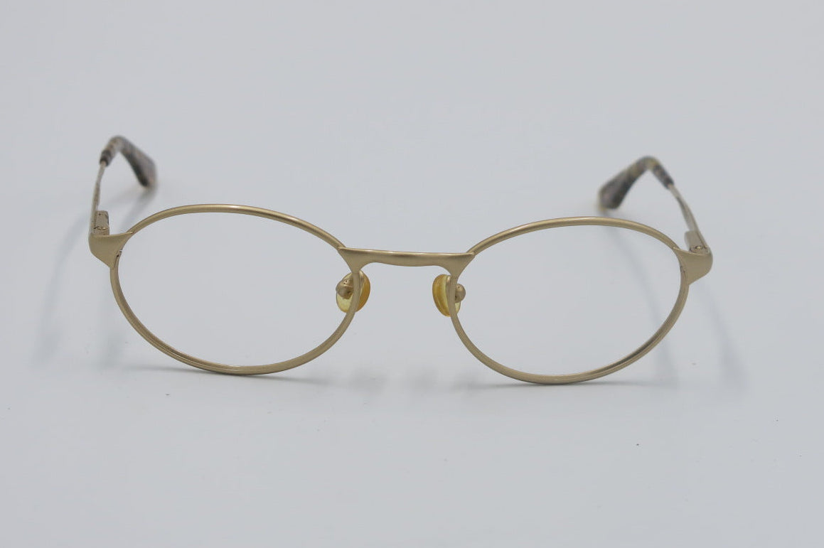 Gold-framed eyeglasses on a light gray background