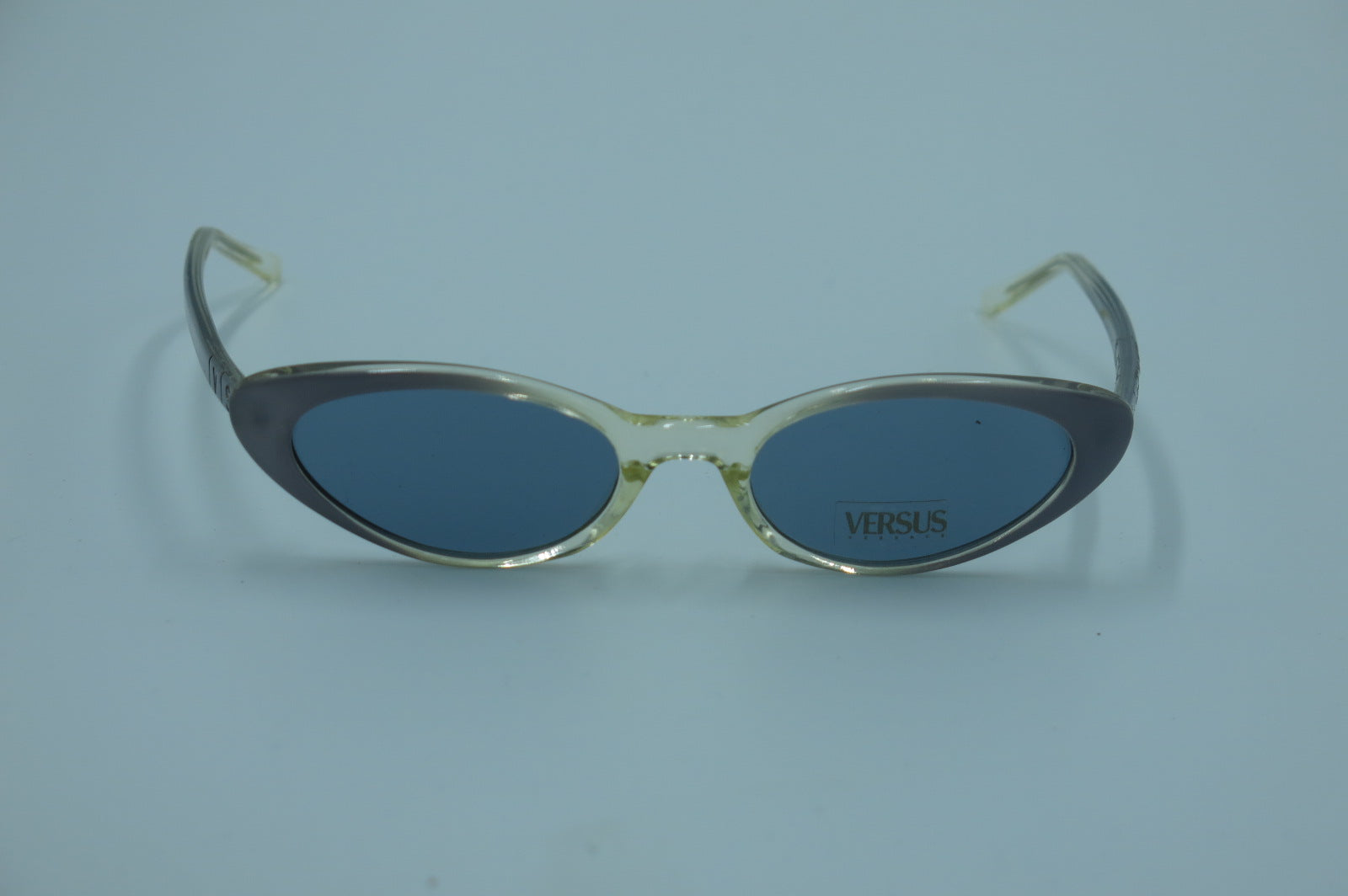 Sunglasses with 'Versus' branding on a light blue background