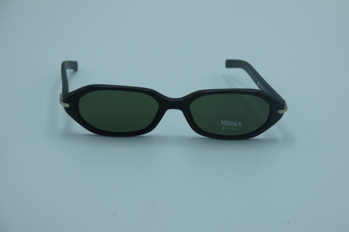 Black sunglasses with green lenses on a light blue background