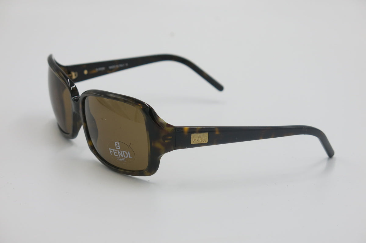 Fendi sunglasses with a dark tortoiseshell frame and brown lenses, featuring the Fendi logo on the lens and a gold-tone brand plaque on the temple.