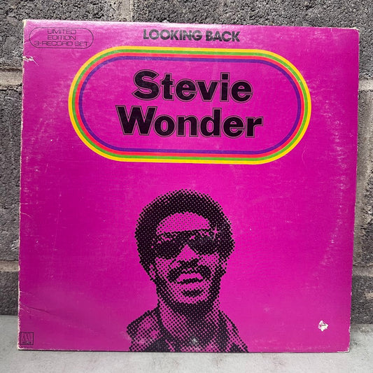 Vinyl record cover for 'Looking Back' by Stevie Wonder with a purple background and black and white portrait.