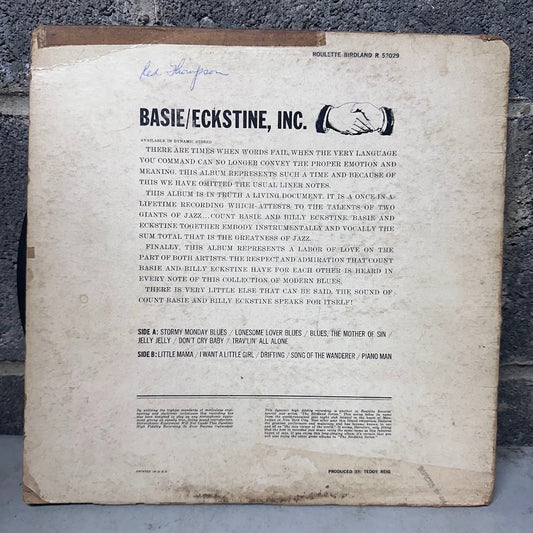 The back cover of a vintage Basie/Eckstine, Inc. record sleeve laid flat on a dark textured surface.