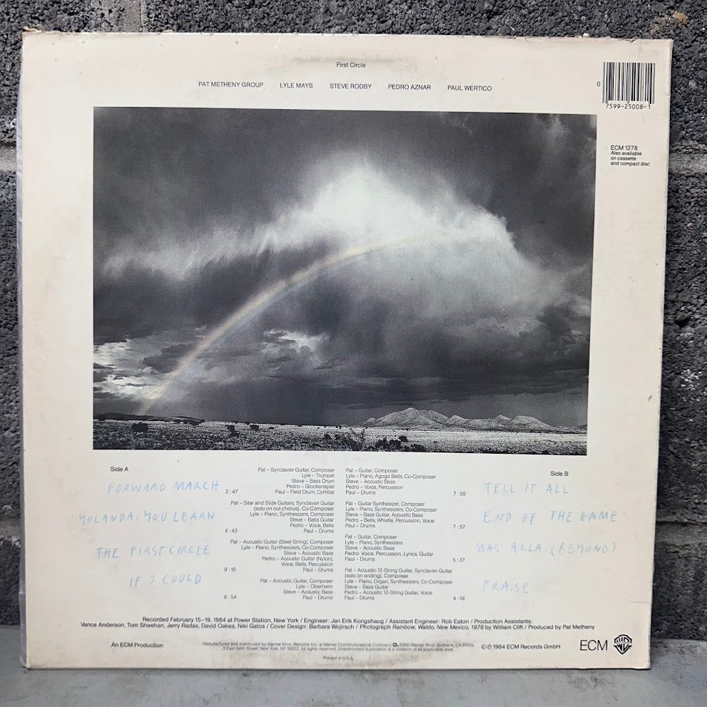 The back cover of a vinyl record sleeve for Paul McCartney's 'Held Back' LP, featuring a dramatic stormy sky with a rainbow over water, photographed on a dark textured surface.