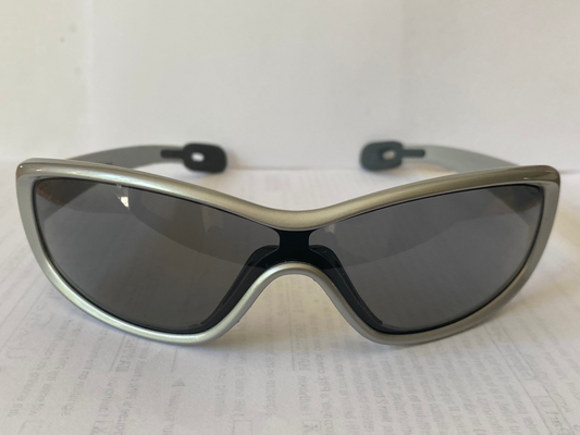 Sunglasses with a silver frame and dark lenses on a white sheet of paper.